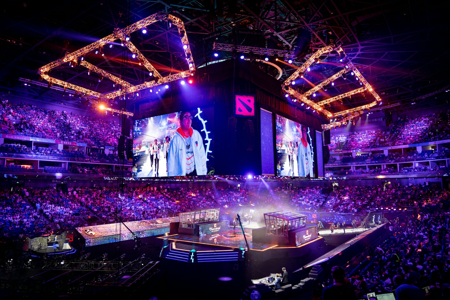 Esports competition in a packed indoor arena with large screens.