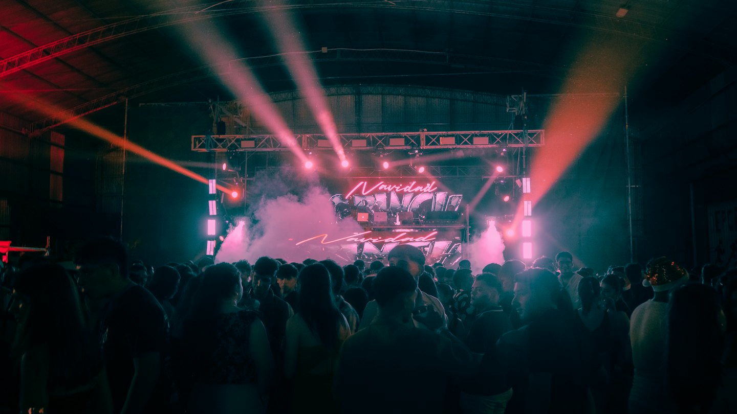Silhouetted crowd at a concert with a brightly lit stage.